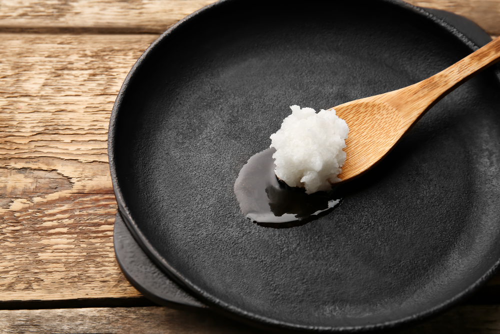 Spoon with coconut oil in frying pan