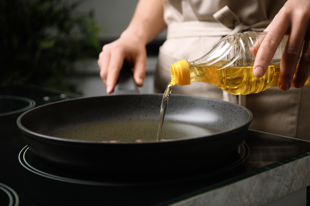 Woman,Pouring,Cooking,Oil,From,Bottle,Into,Frying,Pan,,Closeup