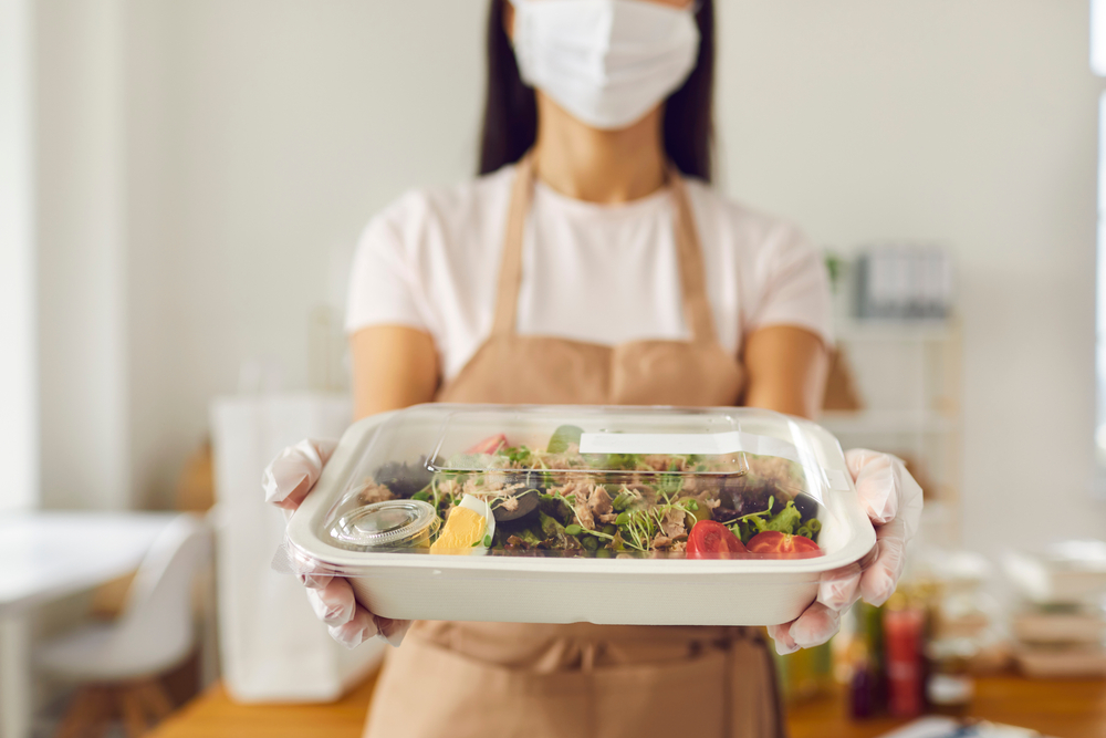 food professional handing a sealed food container