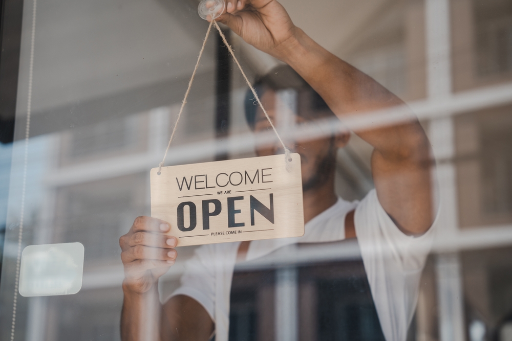 a cafe owner holding an 'open' sign
