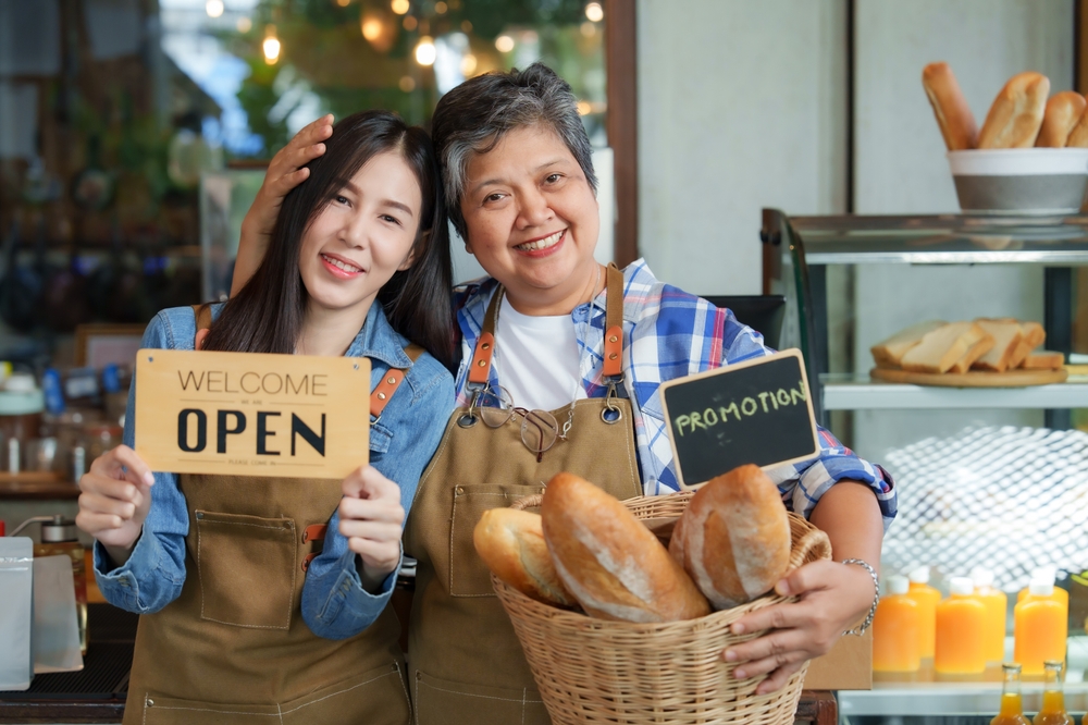 mother and daughter holding a basket of bread and a sign