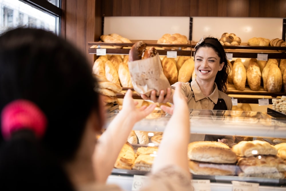 a woman selling pastries to a customer