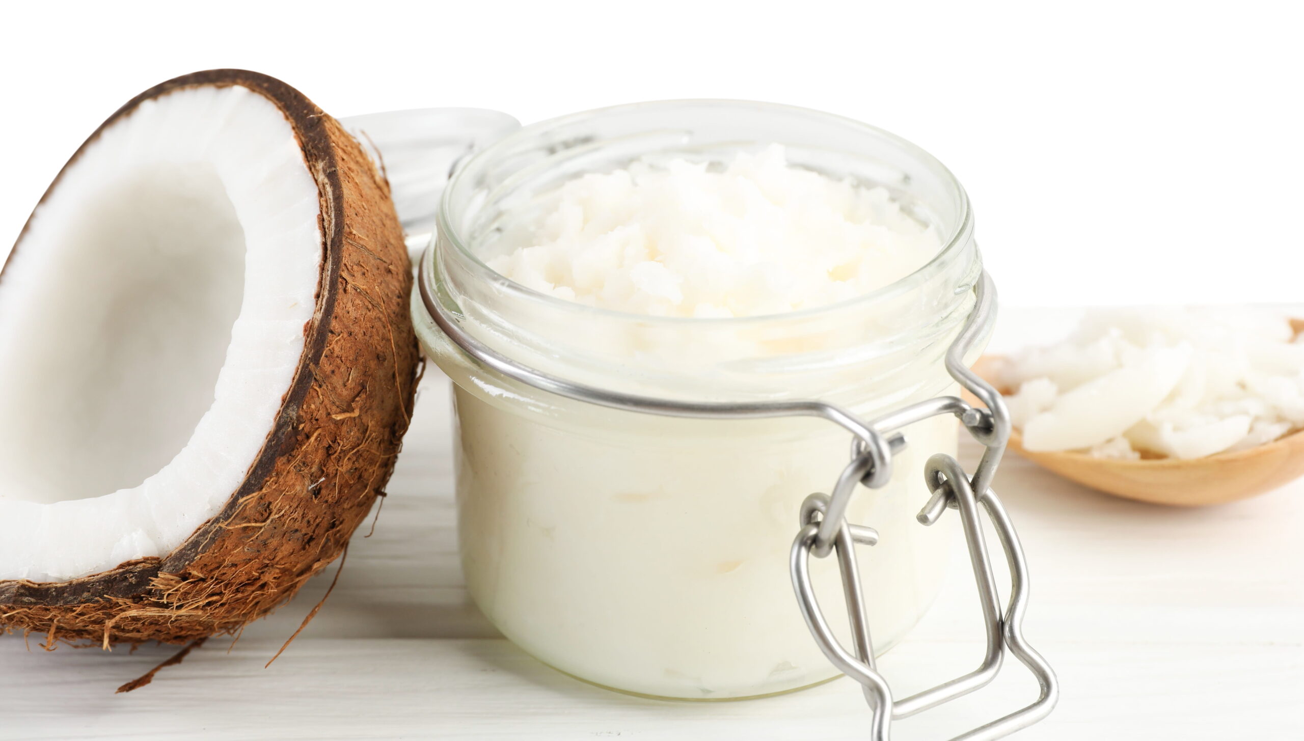 coconut cooking oil in jar, spoon and fresh fruit on wooden table